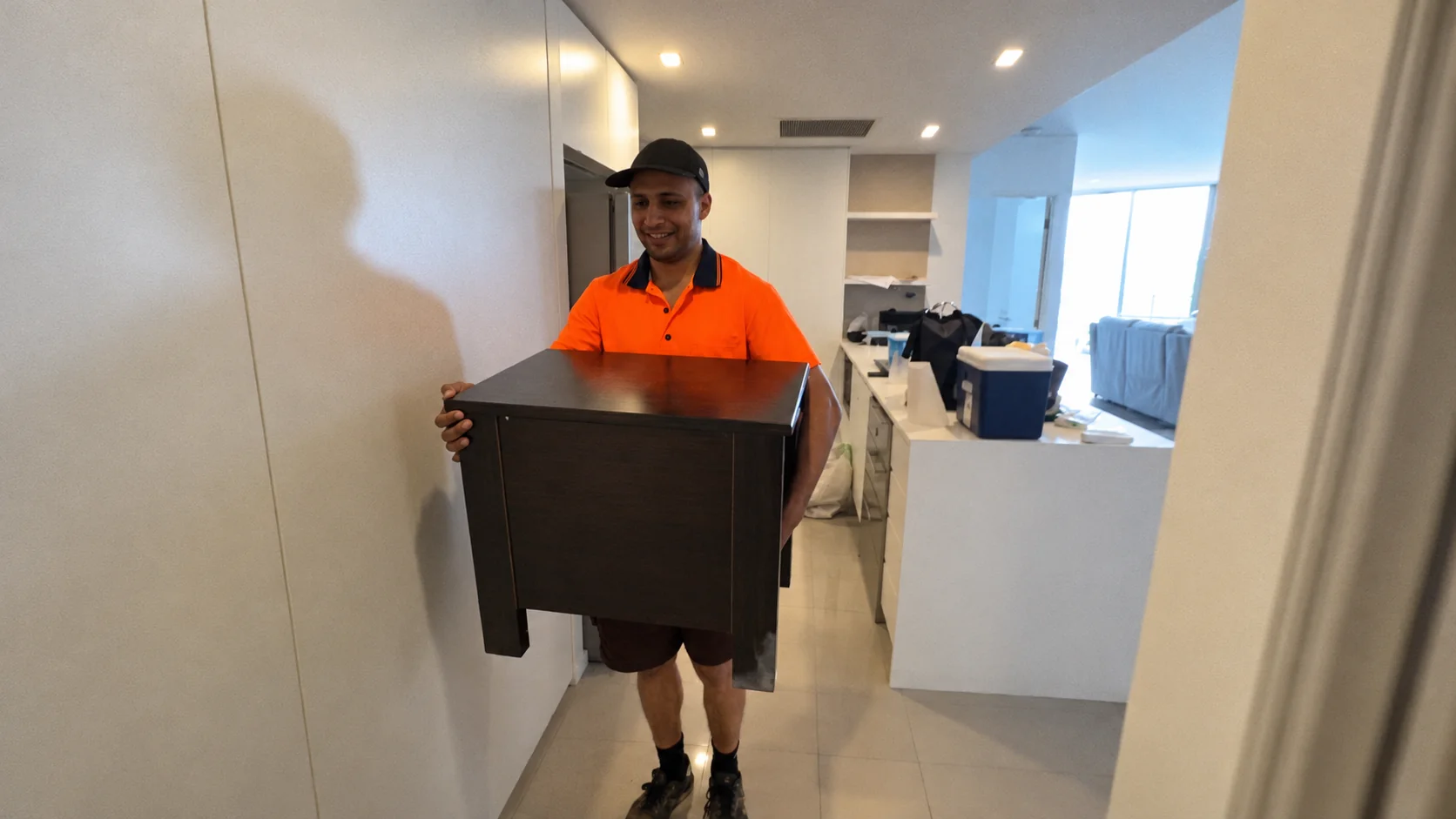 Mover carrying a nightstand through a home